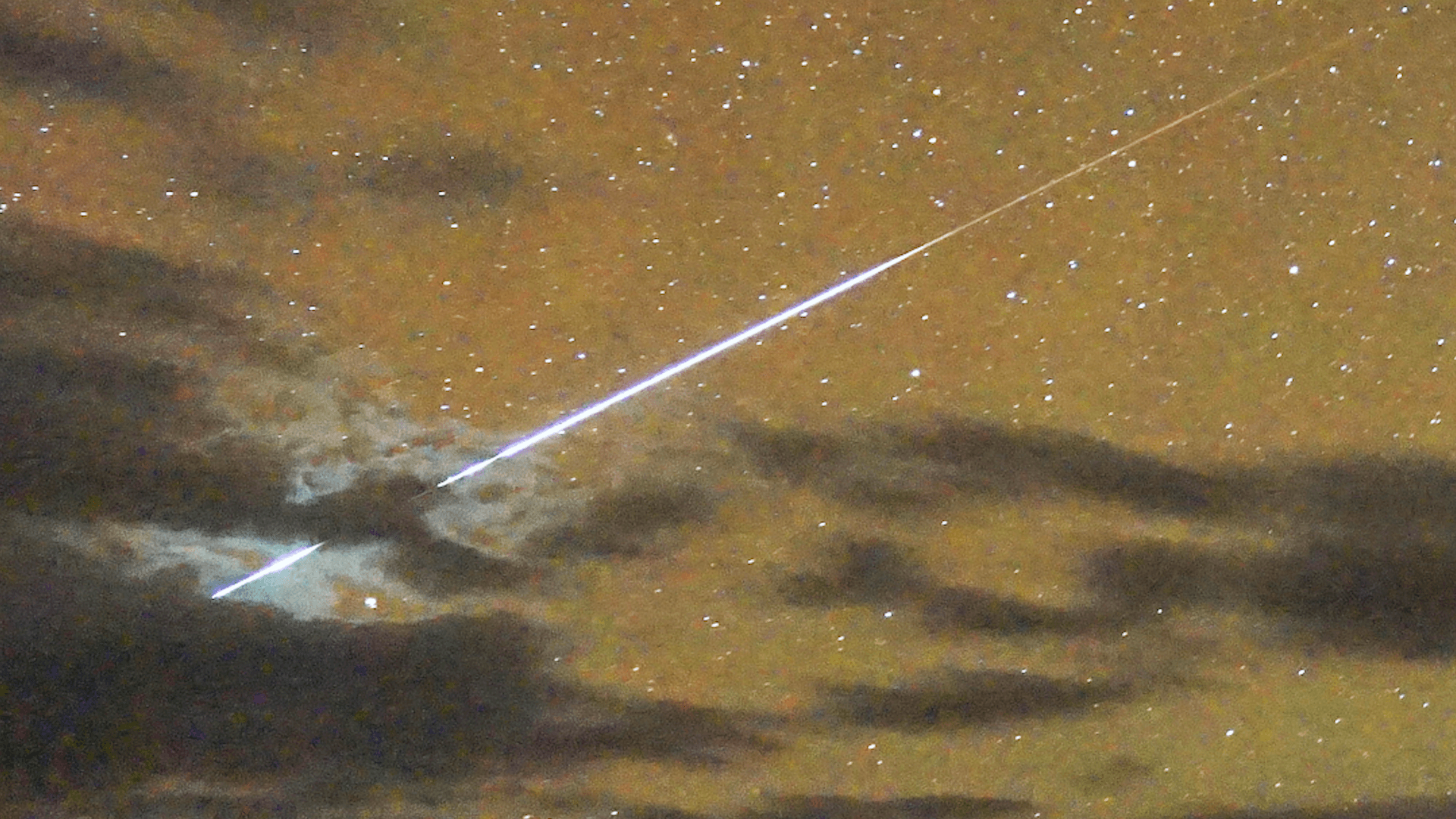 A bright meteor in an orange night sky