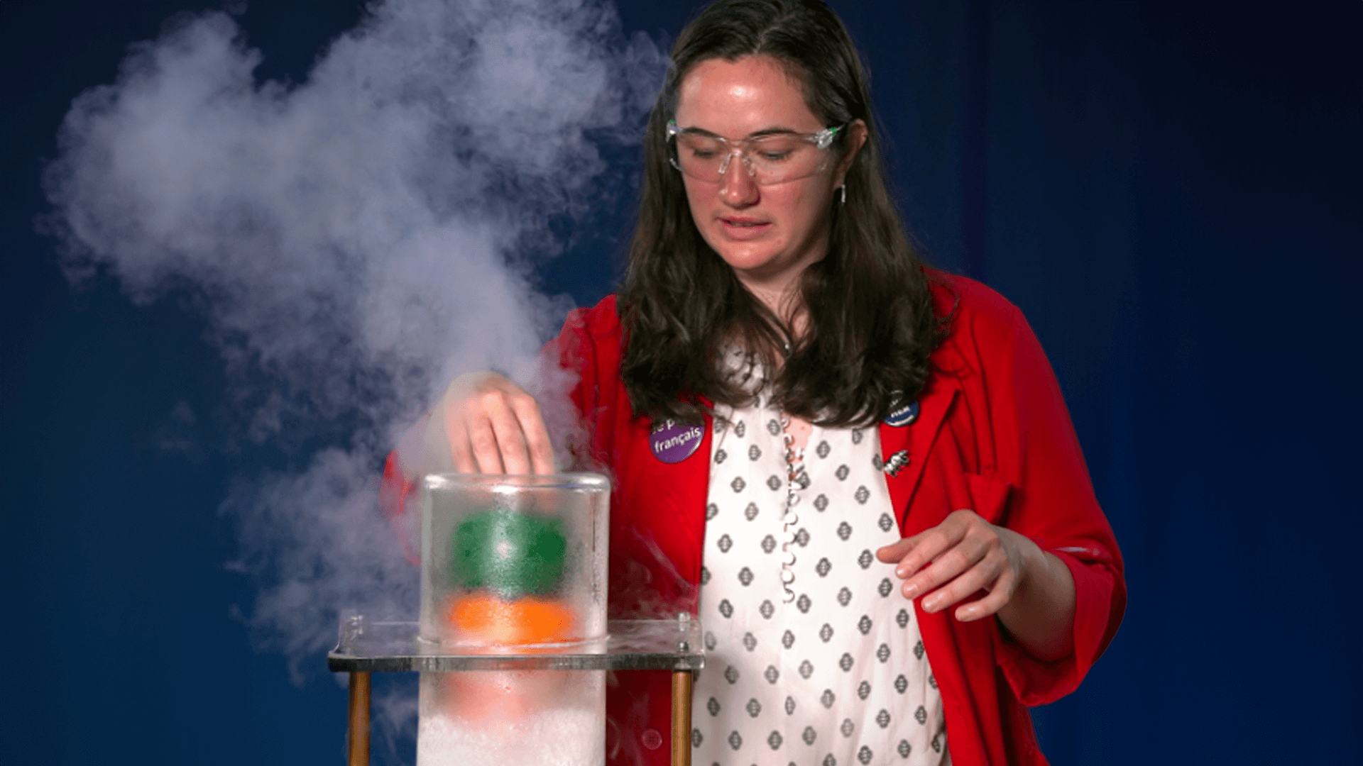 Museum Educator in a red lab coat putting balloons in a tube