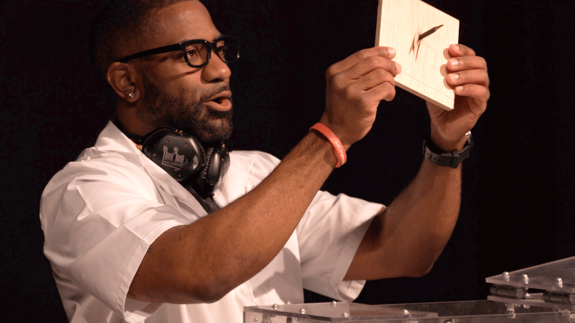 Maynard Okereke holding up a block of wood with a pencil through it 