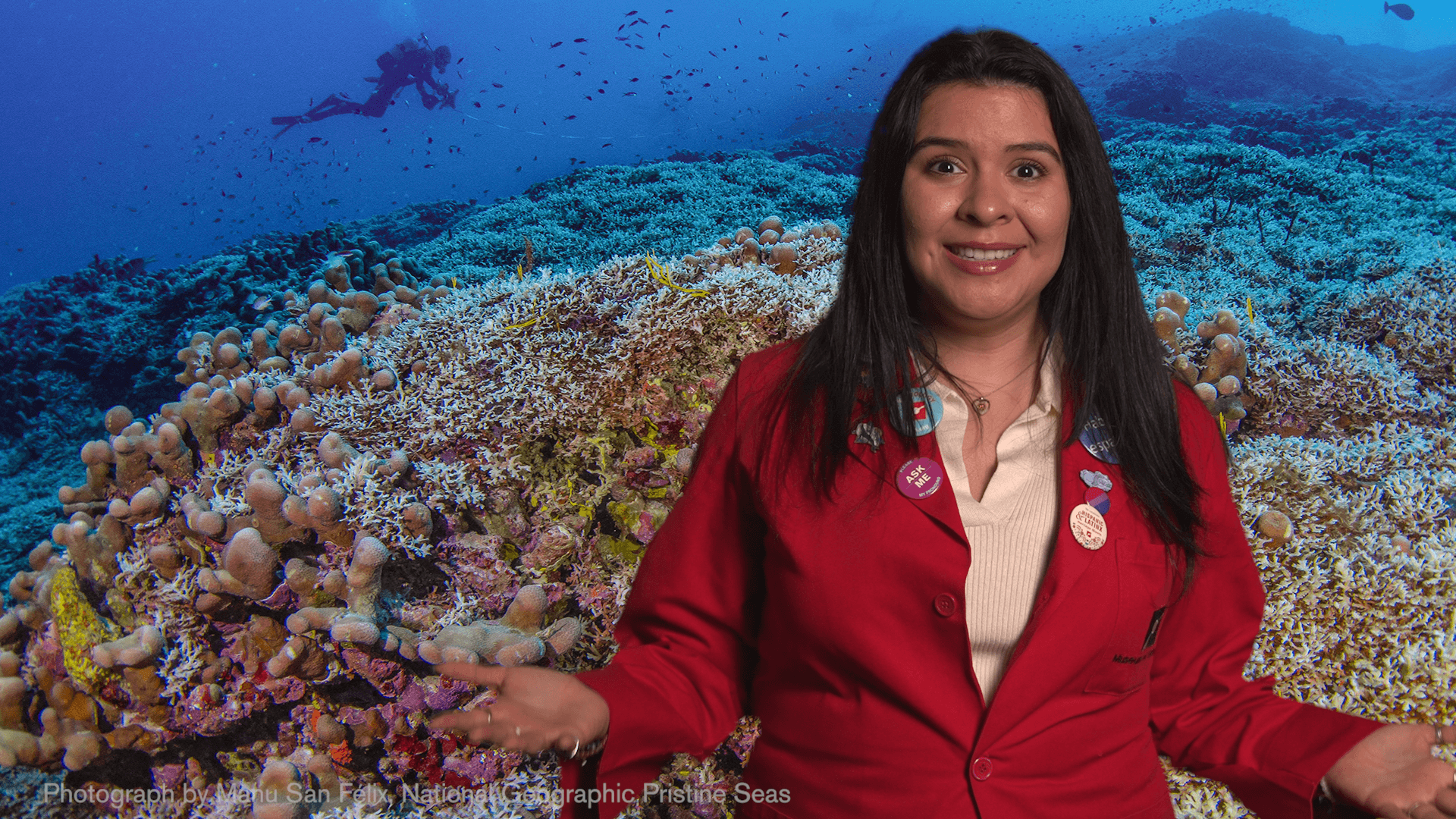 Museum Educator Ana in front of an image of a coral reef