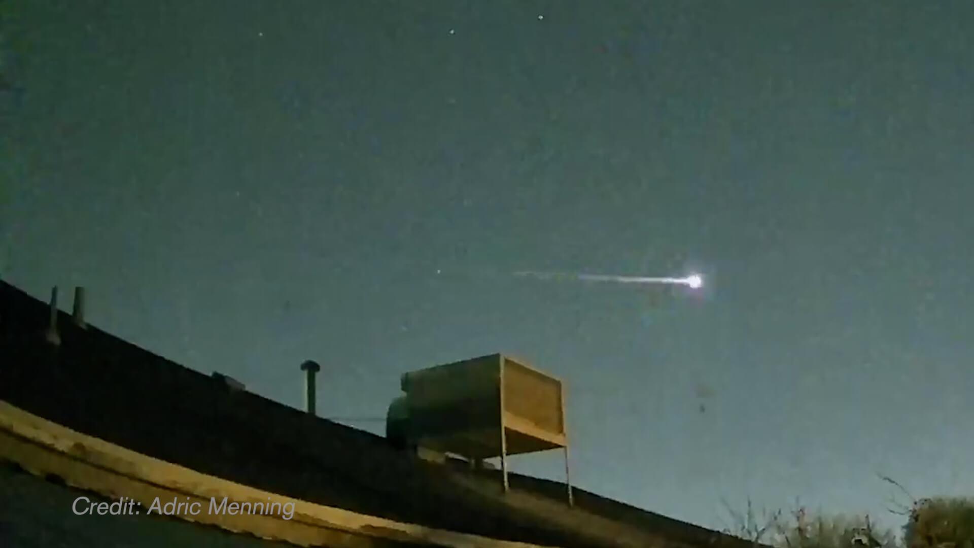 A meteor flies over a house