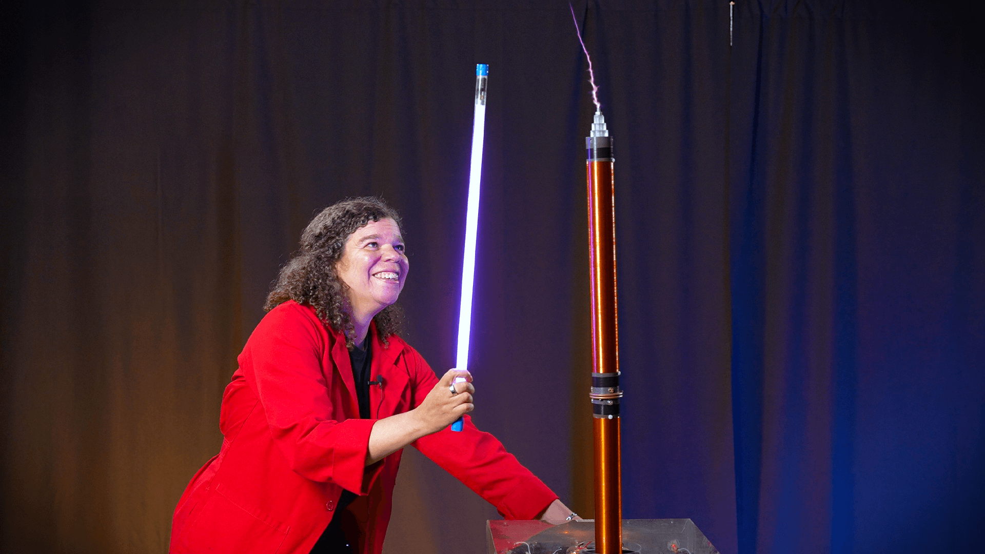 Educator Jeannine with a tesla coil sparking and a glowing light bulb