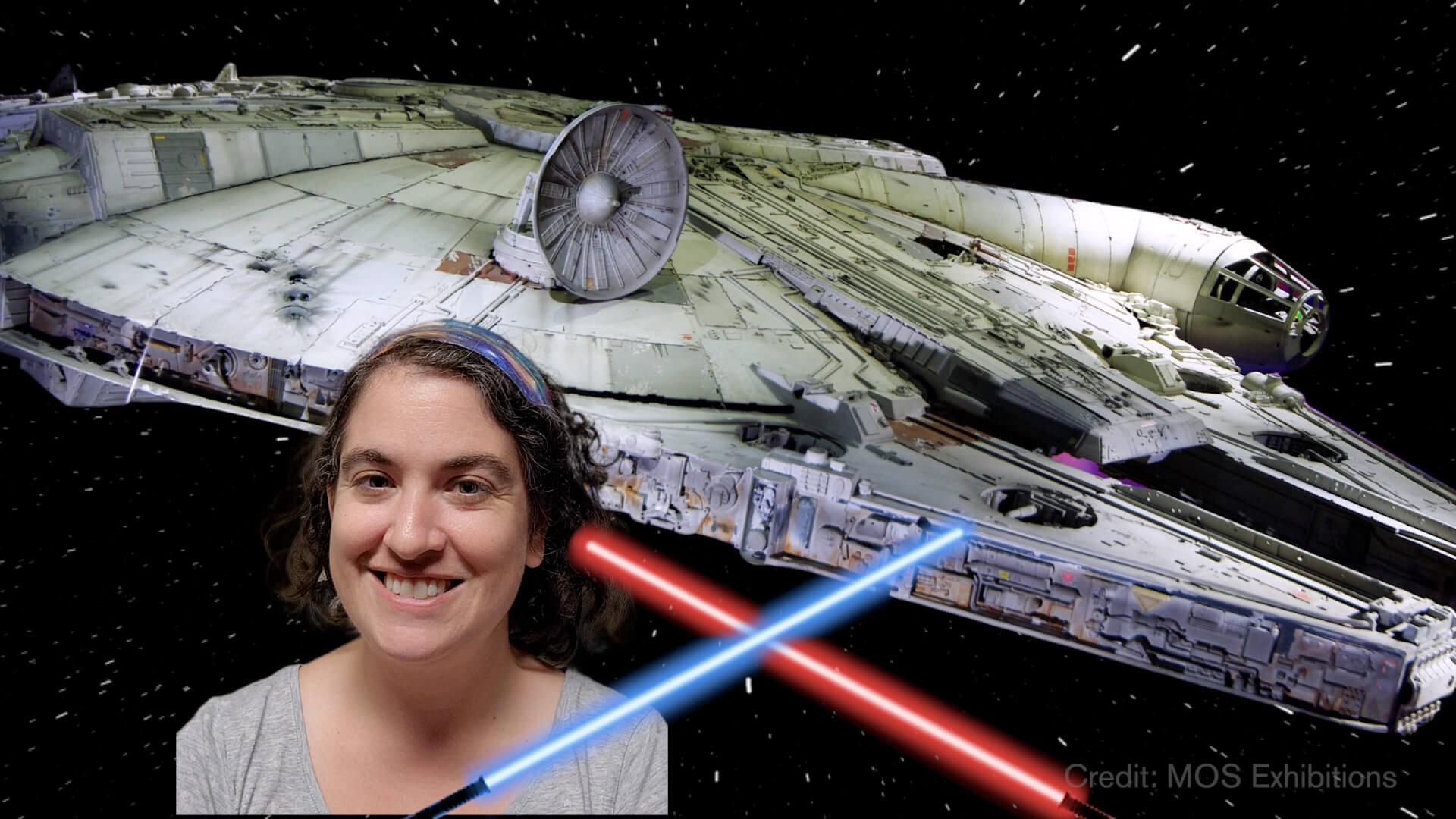 Talia in front of a model of the Millennium Falcon with two light sabers