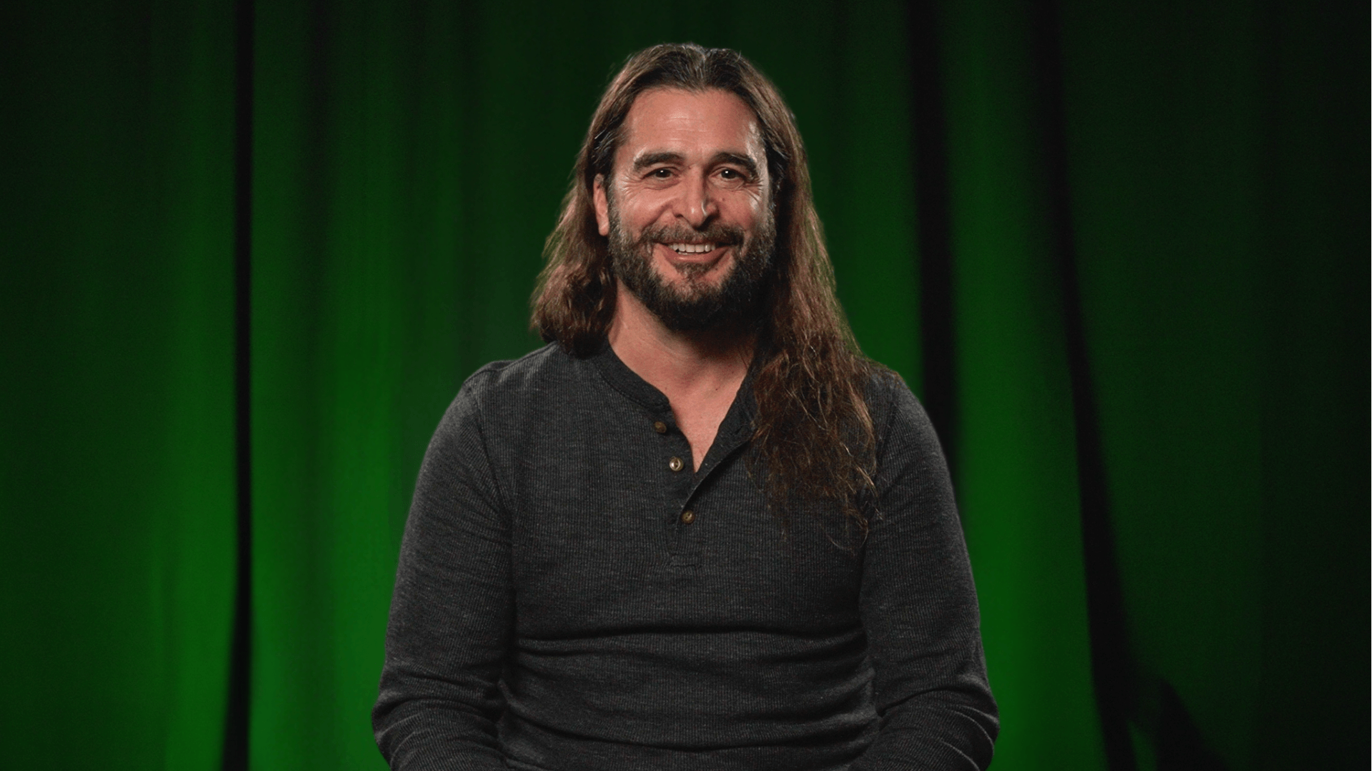 Drew Rollert in front of a black curtain with green lights on it.