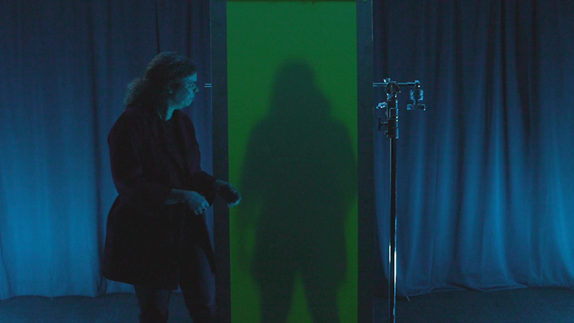 Jeannine stands away from a paper that glows green showing her shadow.