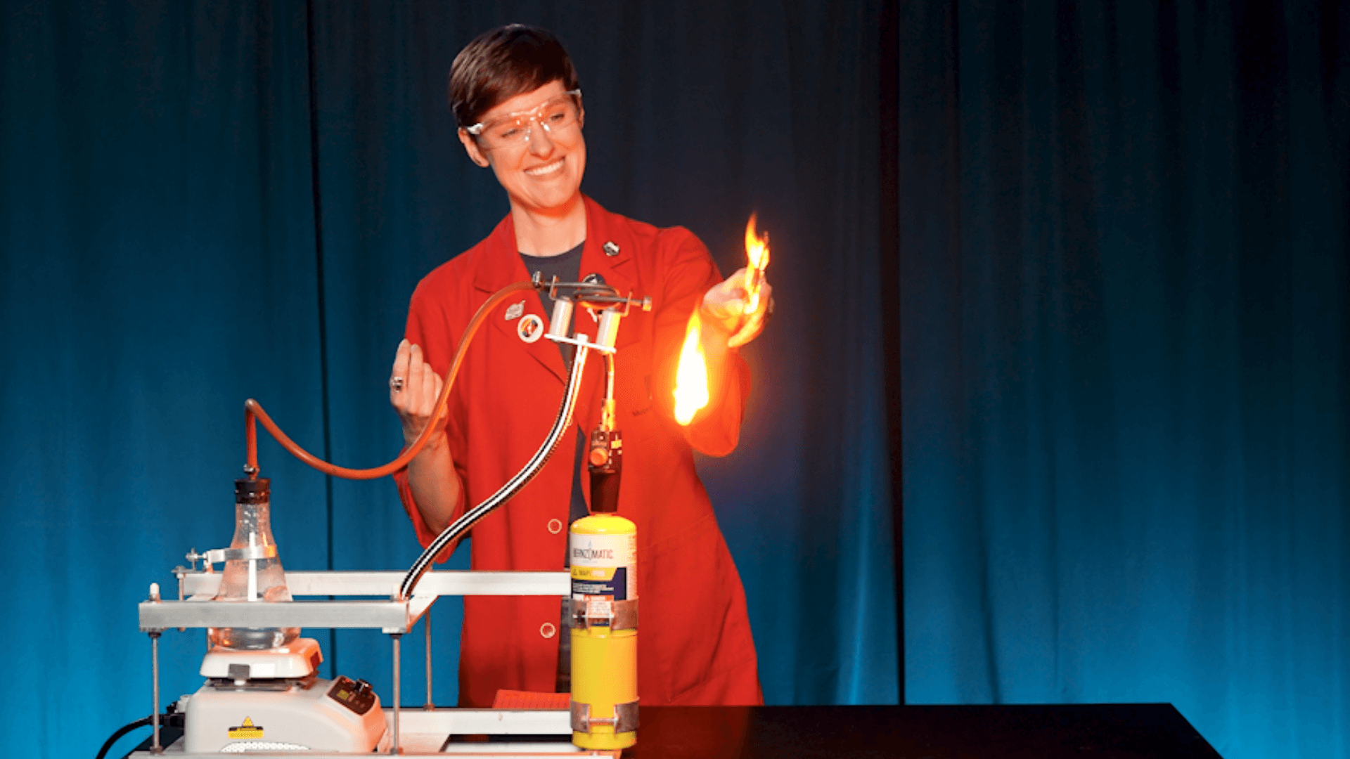 Emily holds a piece of paper to a pipe emitting steam as it catches fire