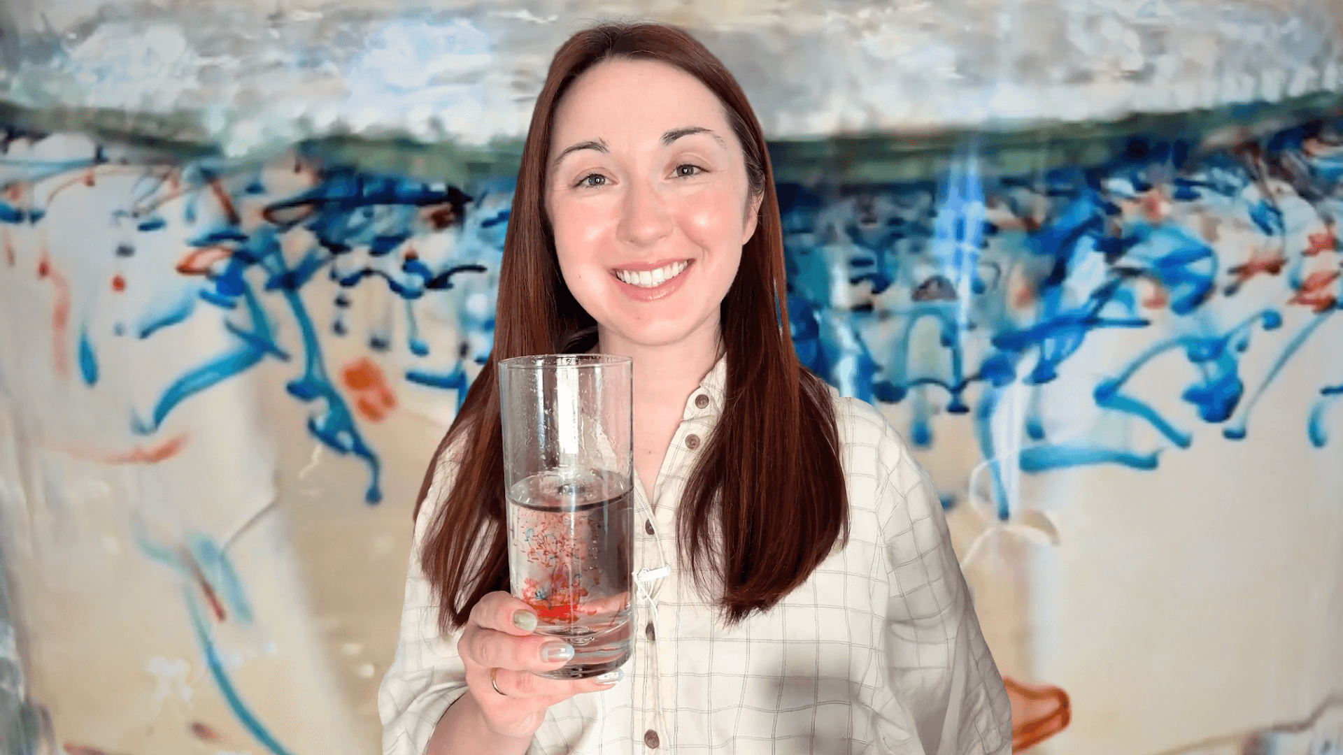 Alex Dainis in front of a glass of water with swirls of blue and red food dye in it.