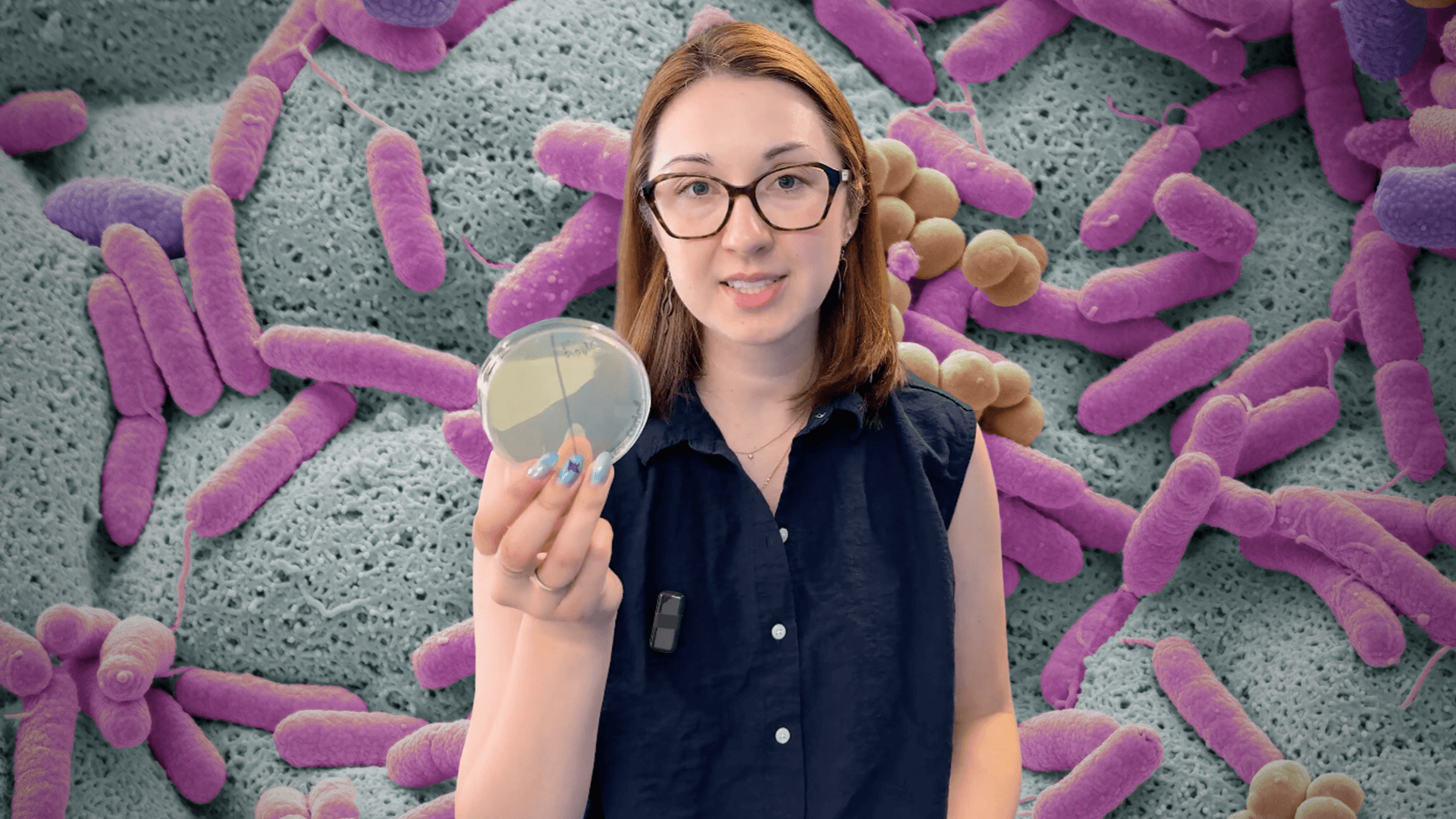 Alex Dainis in front of a microscopic view of bacteria