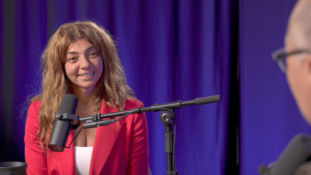 Rana Elkaliouby smiles in front of a purple lit curtain.