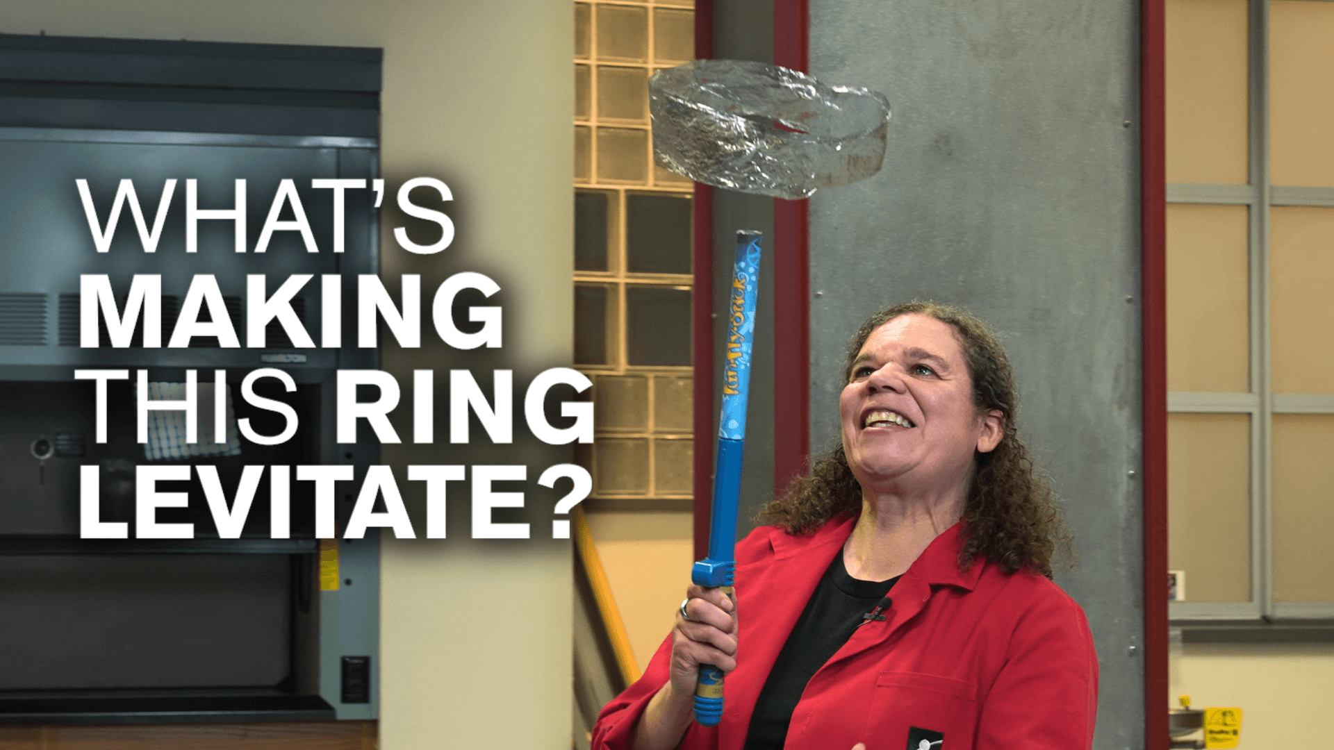 Educator Jeannine with a wand making a metallic ring float with white text reading "Waht's making this ring levitate?"