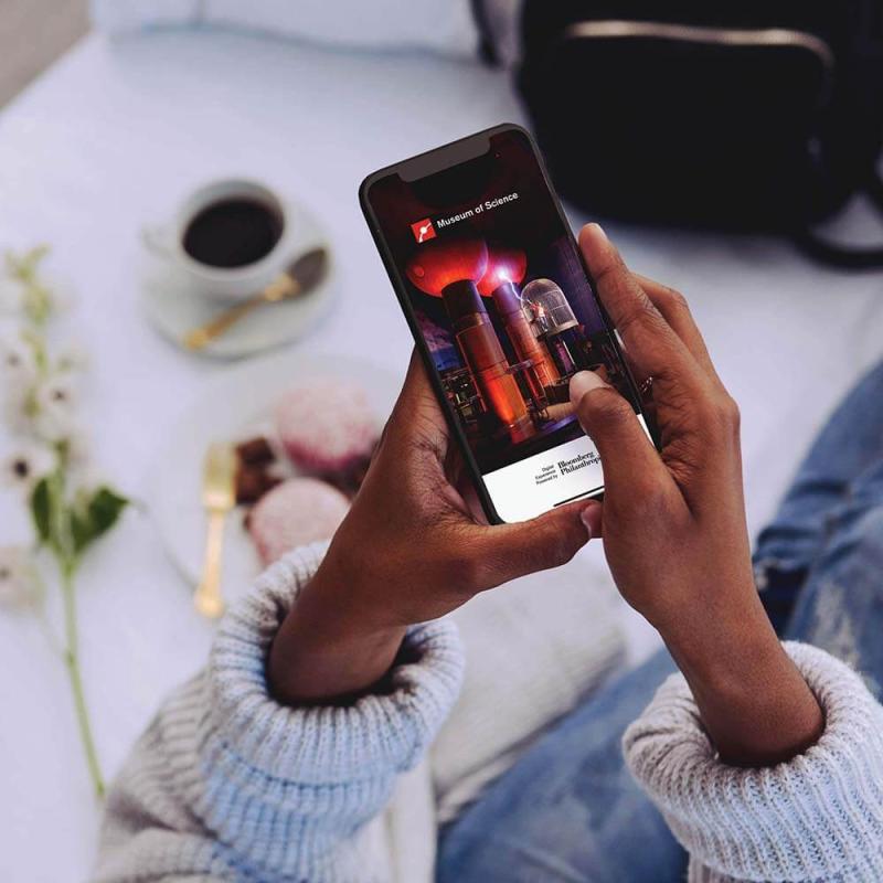 Hands holding a phone with the Bloomberg Connects app open.