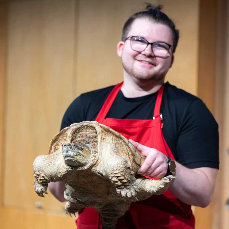 A museum eductaor holding a snapping turtle.