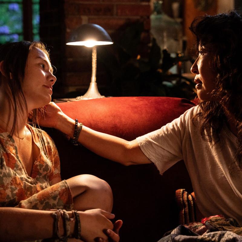 Two women looking at one another on a couch.