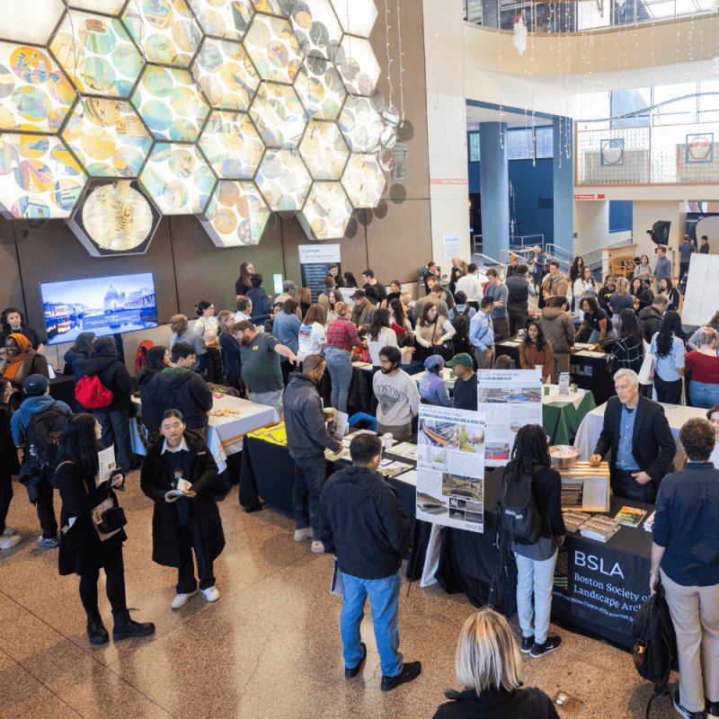 A career fair filled with young professionals networking, engaging in discussions, and exploring job opportunities at various company booths.